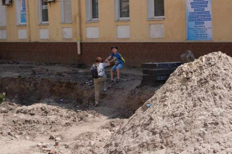 Хлопчик допогає мамі вийти з ями на будівництві у Харкові