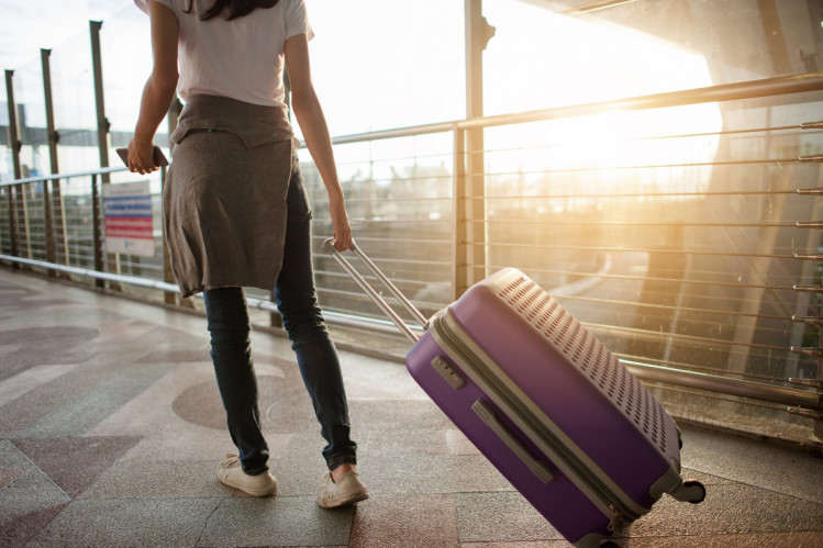 Туристка з чемоданом в аеропорті 