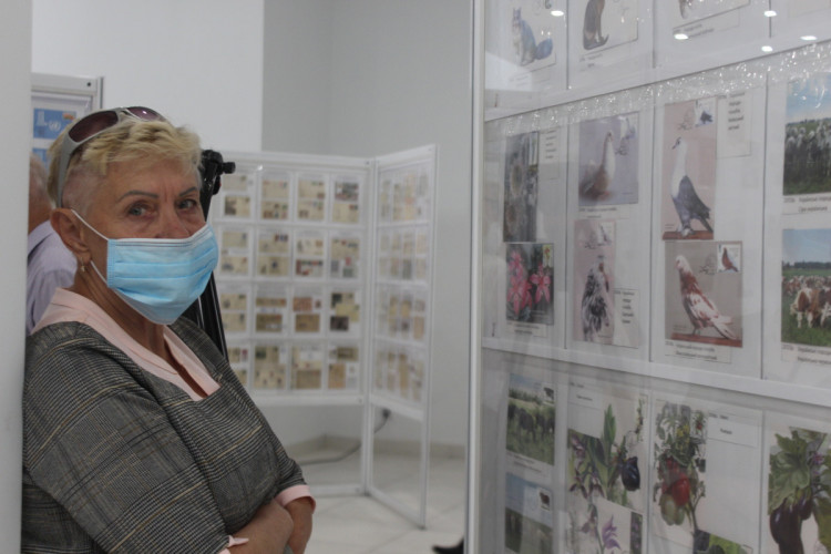 Женщина в маске у стенда на выставке УКРФИЛЕКС 2020